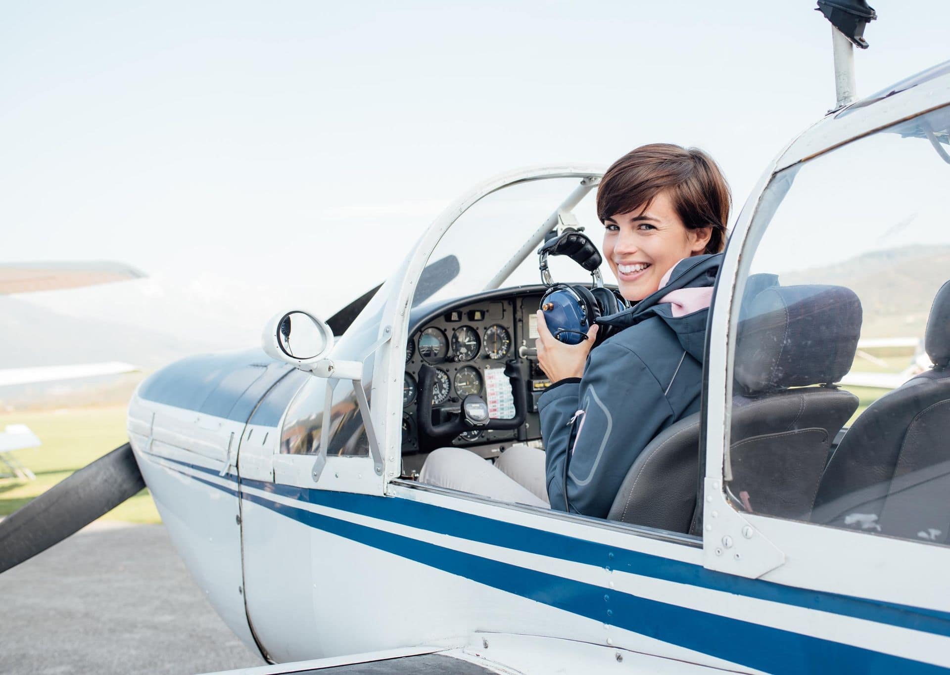 Smiling pilot wearing an aviation headset in the cockpit of a small airplane